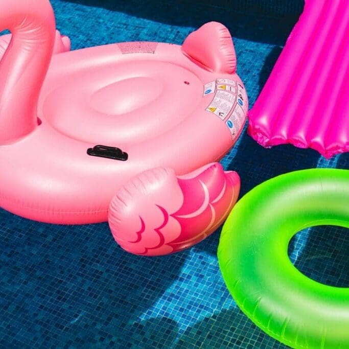 Photo by Toni Cuenca pink inflatable flamingo and green inflatable ring